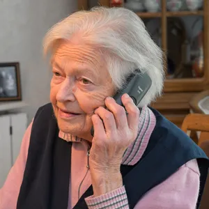 Eine Seniorin ist am Telefon.