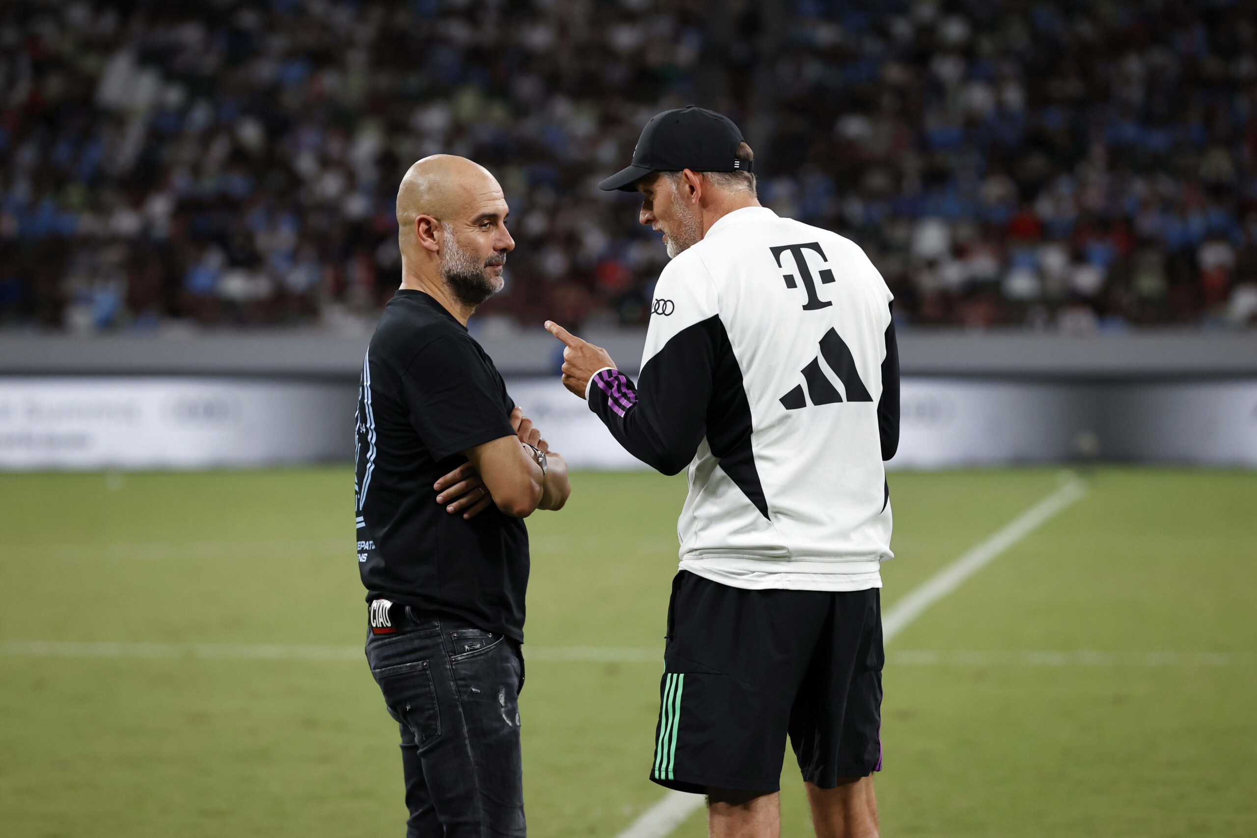 Pep Guardiola und Thomas Tuchel im Gespräch auf dem Spielfeld.