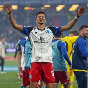 HSV-Stürmer Robert Glatzel steht mit ausgebreiteten Armen vor der Nordtribüne