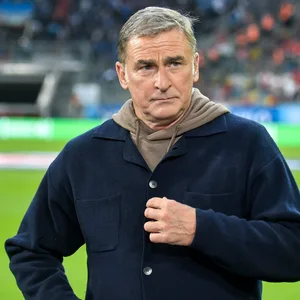 Stefan Kuntz guckt als TV-Experte am Spielfeldrand an der Kamera vorbei