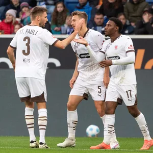 Karol Mets, Hauke Wahl und Oladapo Afolayan klatschen sich nach einem Treffer des FC St. Pauli ab