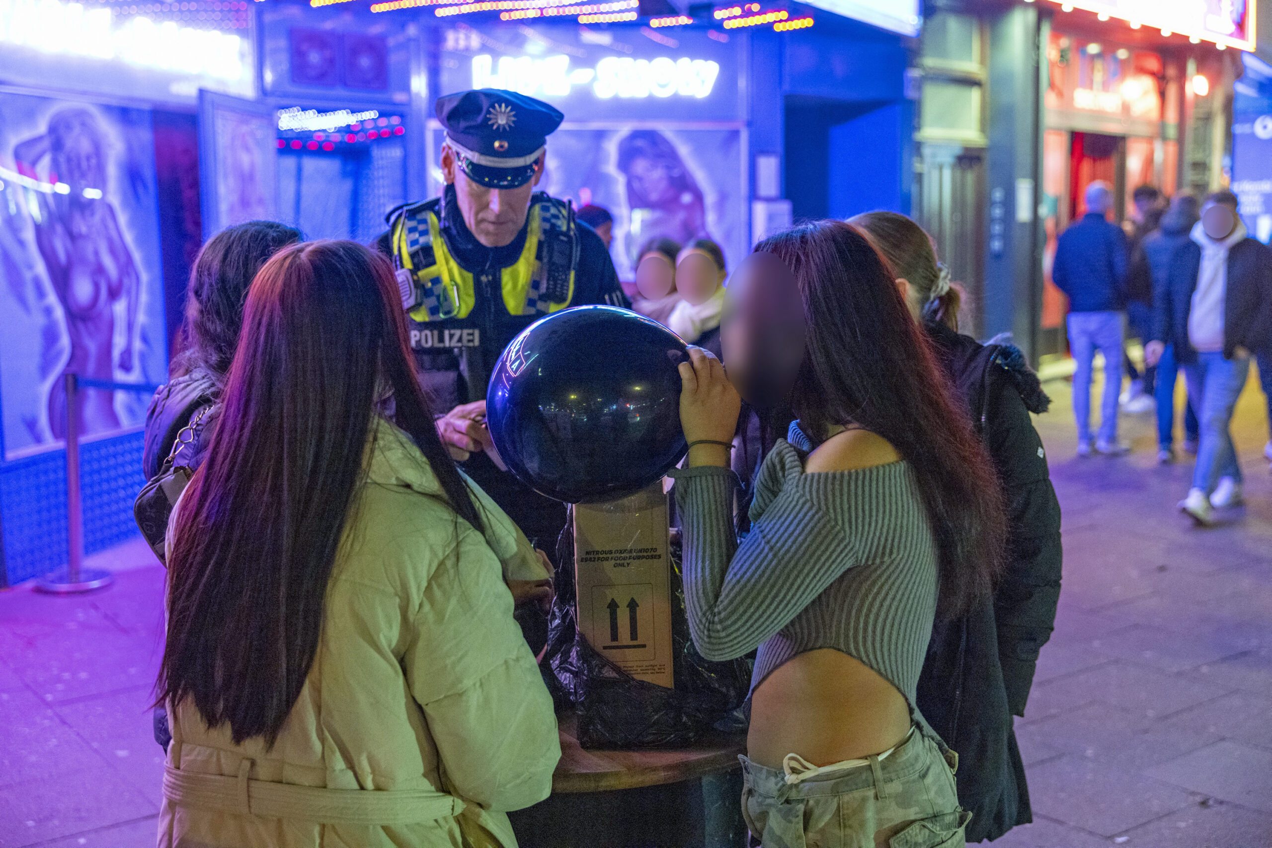 Auch in Hamburg ist Lachgas beliebt – hier konsumieren Jugendliche die Party-Droge vor den Augen eines Polizisten auf der Reeperbahn.