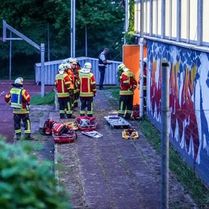 Remshalden: Rettungskräfte stehen vor einer Turnhalle. Vier Kinder sind durch das Dach einer Sporthalle gefallen und schwer verletzt worden.