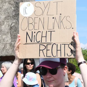 „Sylt. Oben links. Nicht rechts", steht auf dem Plakat einer Teilnehmerin der Mahnwache am Sonntag auf der Straße Strönwai.