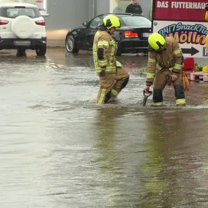 Feuerwehrmänner versuchen, eine überflutete Straße frei zu bekommen.