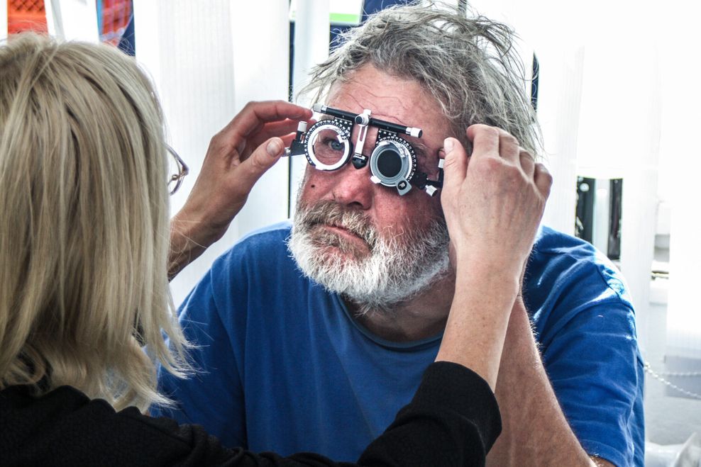 Brillen für Bedürftige: Eine ehrenamtliche Optikerin setzt einem Gast bei der Sprechstunde die Prüfbrille auf.