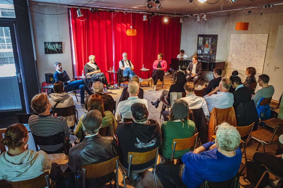 Fünf Podiumsgäste, dazu das Publikum von hinten