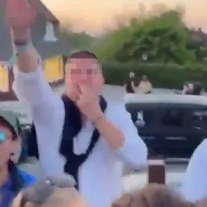 Ein Mann deutet mit seinen Fingern einen Hitlerbart an, während er den verbotenen Hitlergruß zu zeigen scheint – und grölt dabei „Deutschland den Deutschen, Ausländer raus“