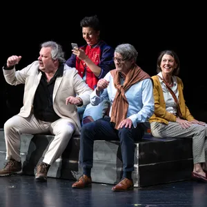 Vier Menschen auf der Bühne, sitzen auf einem Podest