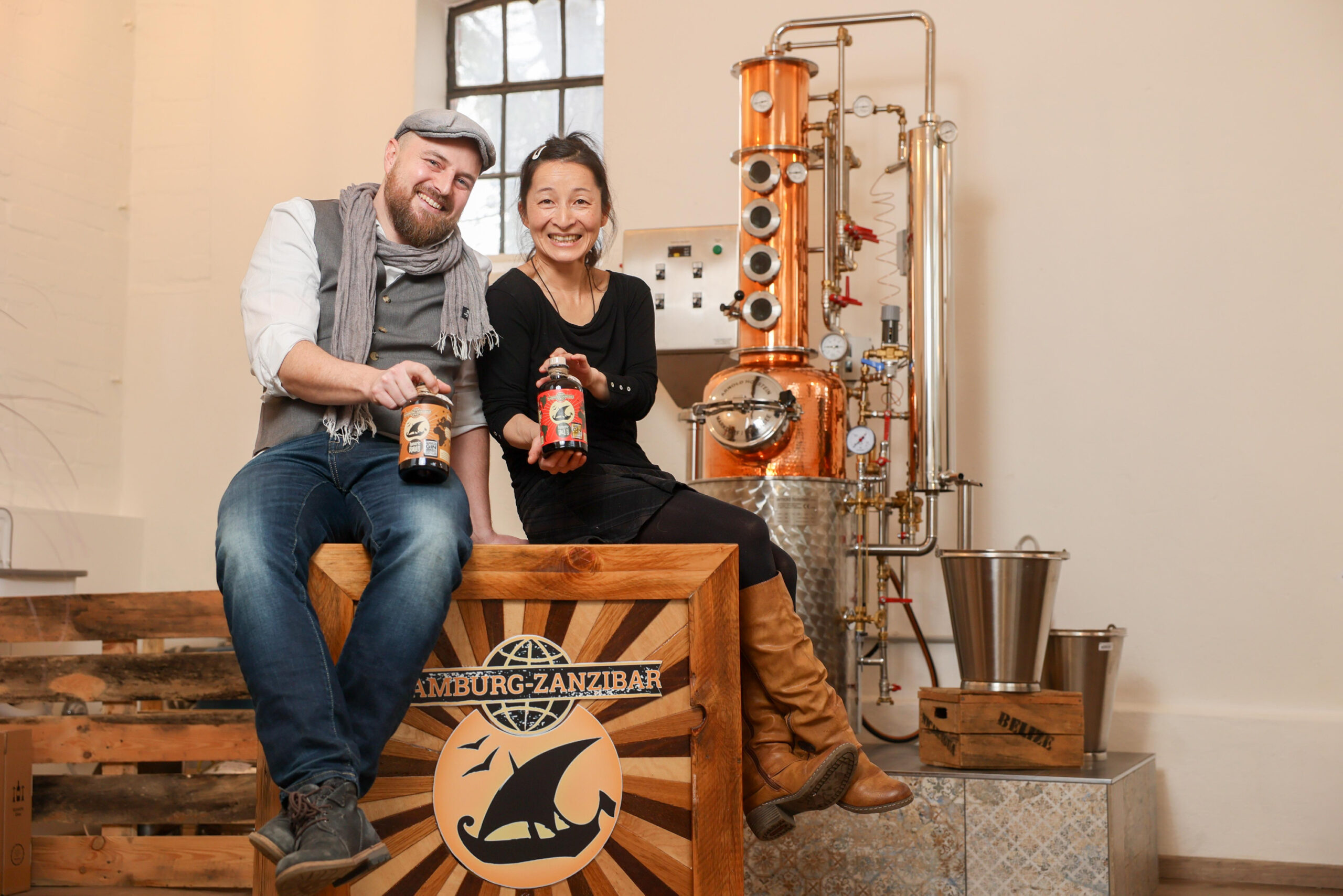 Hauke Günther (45) und Yuka Suzuki (50) mit einer Gin- und einer Rumflasche in ihrer Destillerie