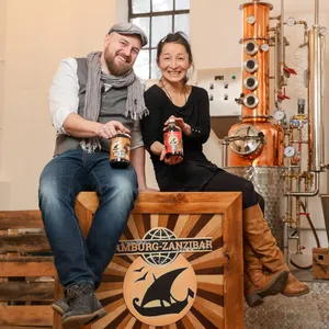 Hauke Günther (45) und Yuka Suzuki (50) mit einer Gin- und einer Rumflasche in ihrer Destillerie