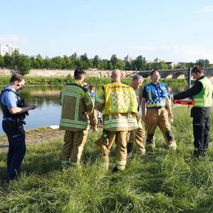 Rettungskräfte stehen am Elbufer.