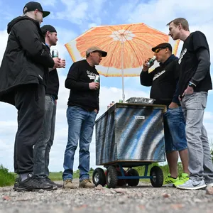 Vatertagstour mit Bollerwagen: Fünf Männer stehen auf einem Feldweg an einem Bollerwagen