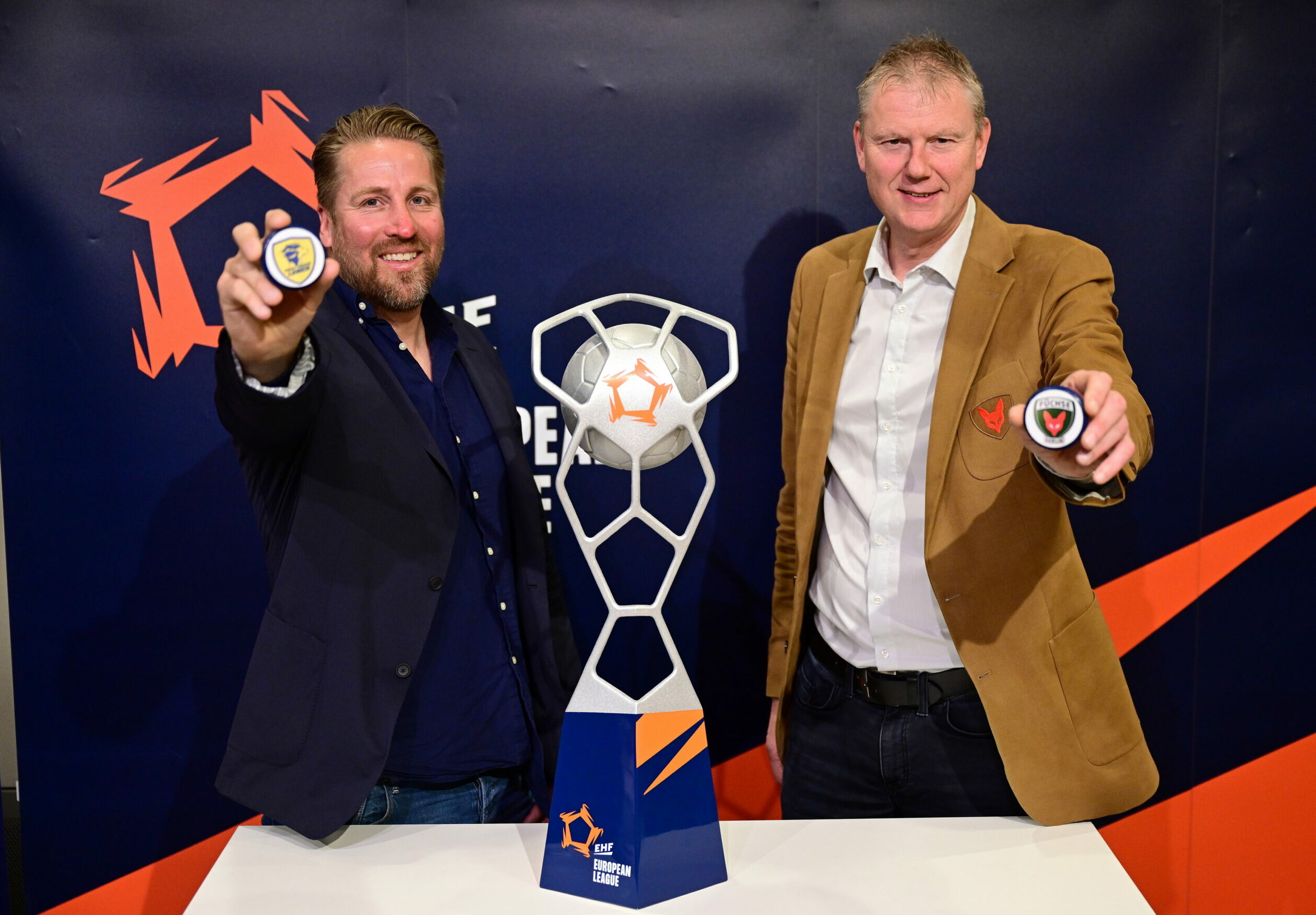 Oliver Roggisch von den Rhein-Neckar Löwen (l.) und Volker Zerbe von den Füchsen Berlin posieren nach der Auslosung der EHF Finals mit dem Pokal