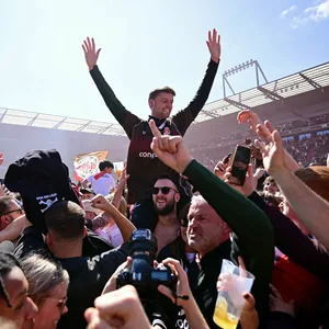St. Pauli-Trainer Fabian Hürzeler wird von Fans auf Schultern über den Stadionrasen getragen