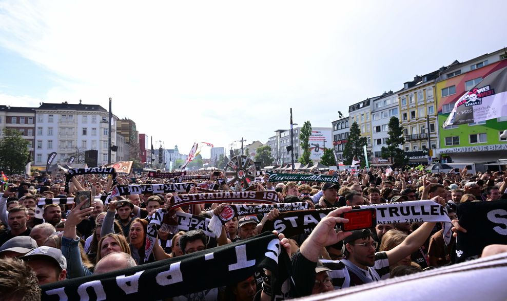 Fans recken ihre St. Pauli-Schals auf dem Spielbudenplatz in die Höhe  