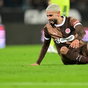 Elias Saad sitzt auf dem Rasen