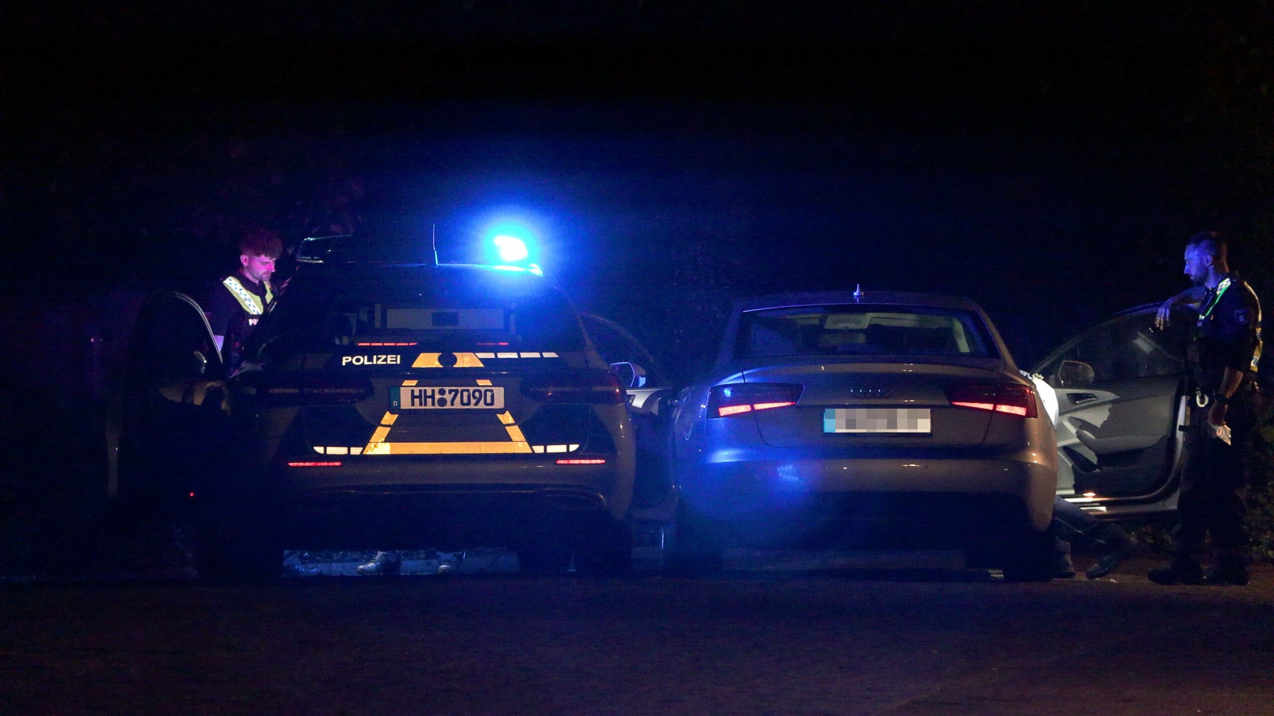 Polizisten stehen nach der Verfolgungsjagd neben dem Audi.