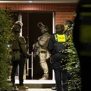 Vor der Tür das Wohnhauses stehen SEK und Polizeibeamte.