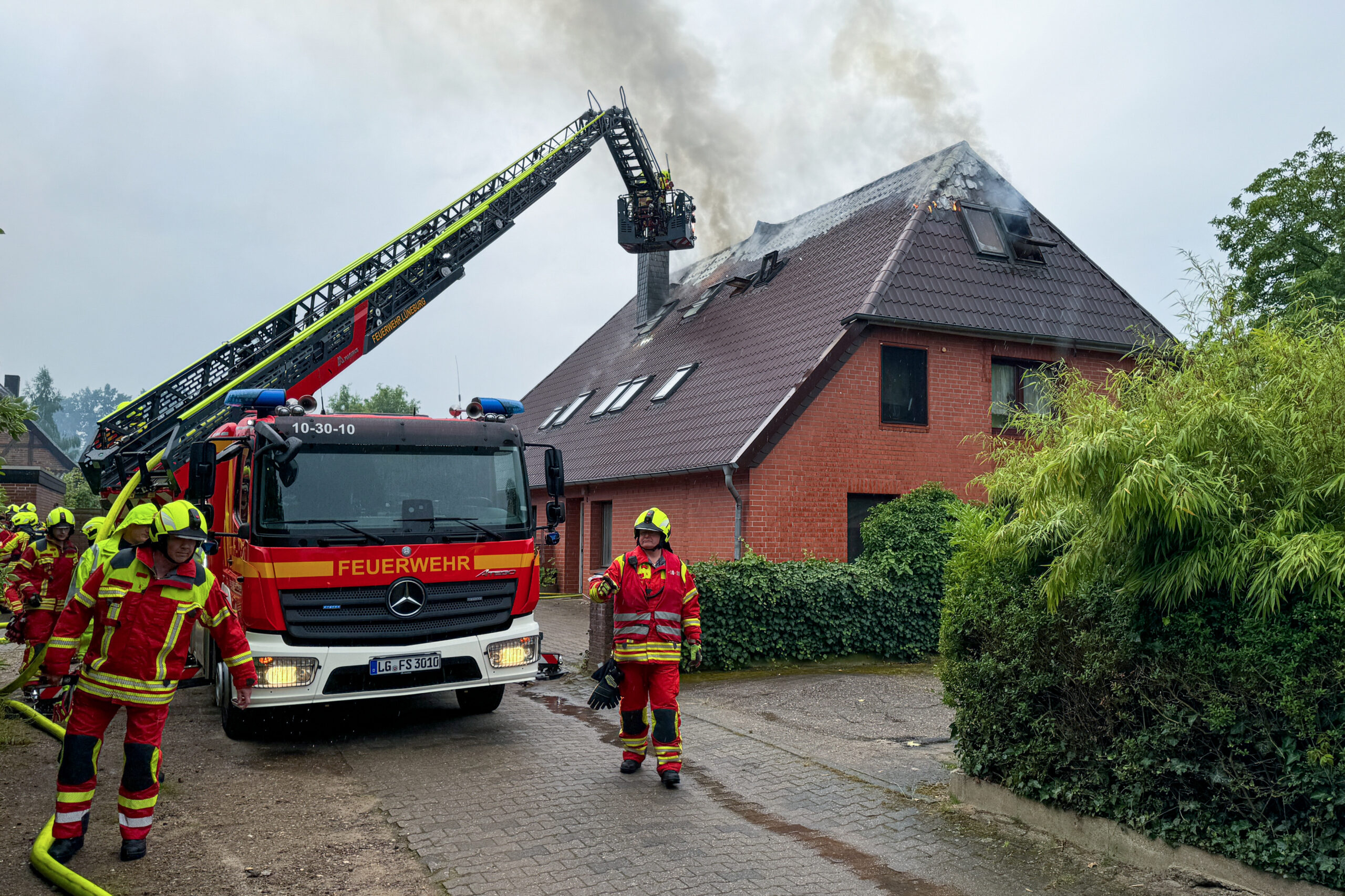 Feuerwehrleute löschen das brennende Mehrfamilienhaus in Lüneburg.