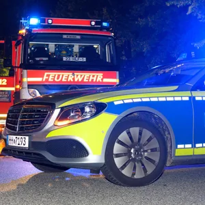 Ein Streifenwagen der Polizei und ein Fahrzeug der Feuerwehr im Einsatz (Archivbild).