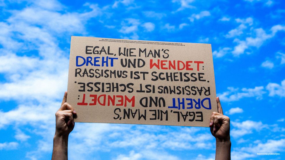 Demo-Schild About You-Kampagne „Egal wie man's dreht und wendet: Rassismus ist scheiße“