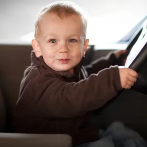 Ein kleiner Junge sitzt in einem Auto am Steuer.