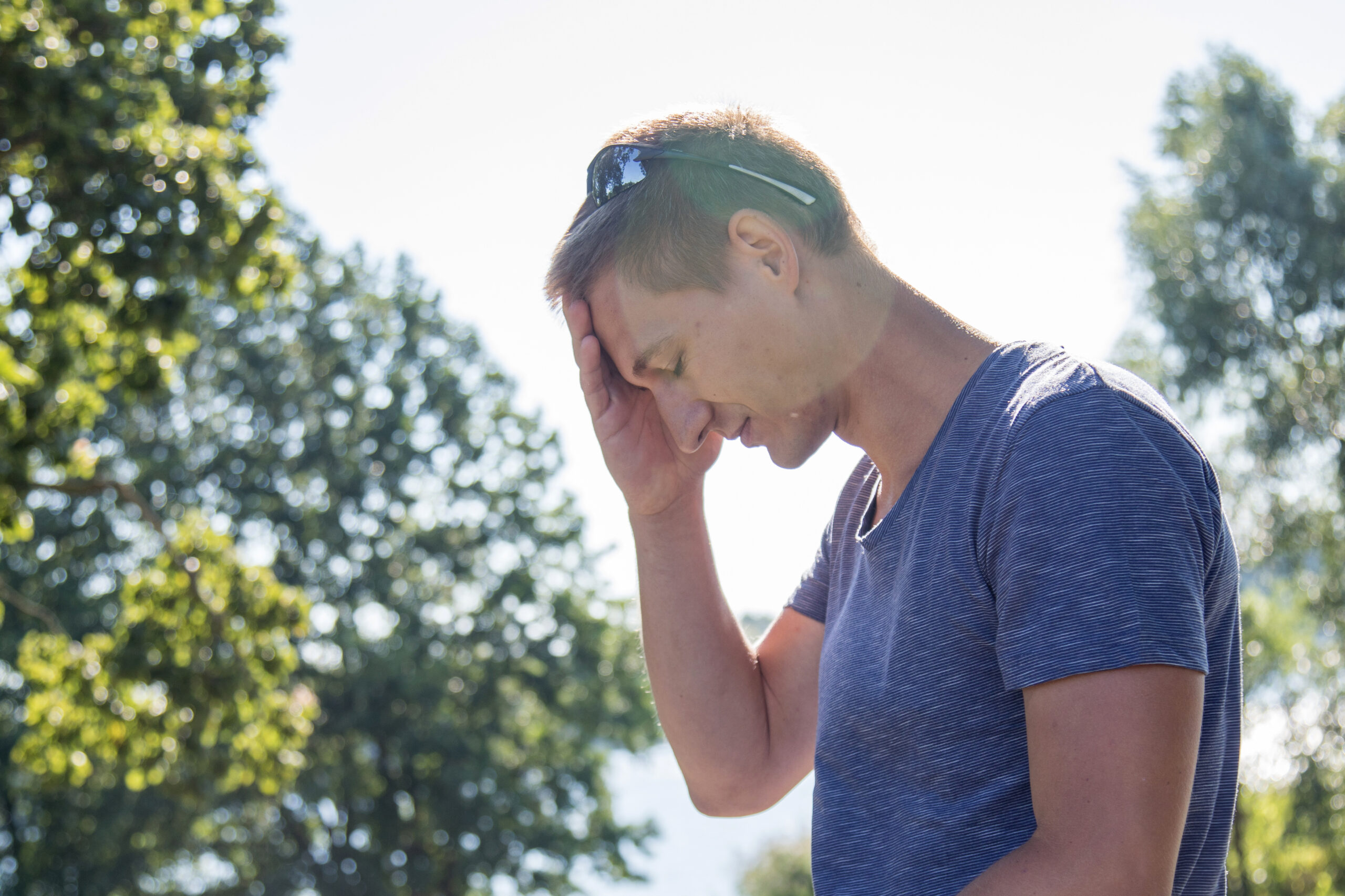 Ein Mann leidet wegen der Sonne unter Kopfschmerzen.