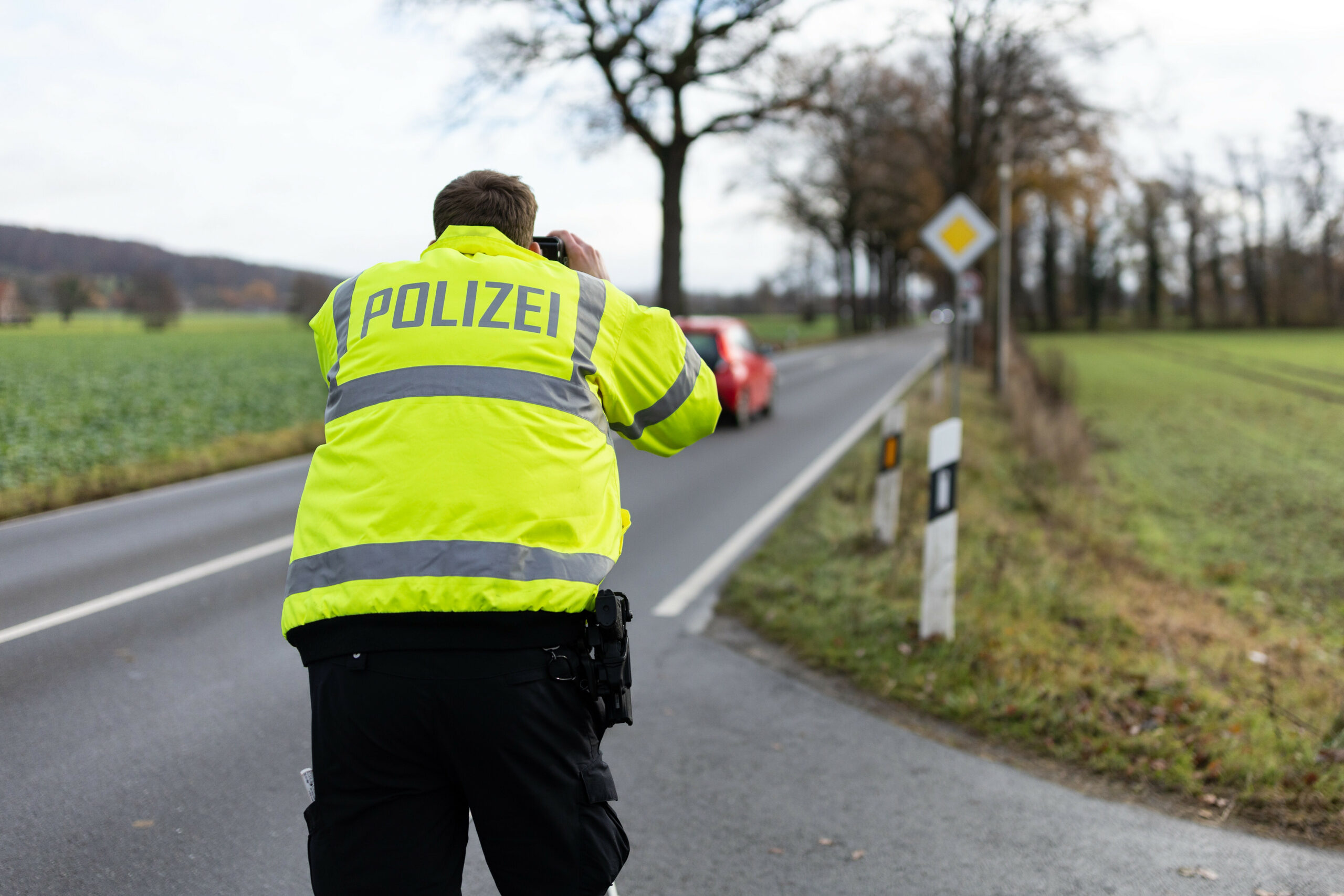 Ein Polizist misst die Geschwindigkeit vorbeifahrender Autos (Symbolbild).