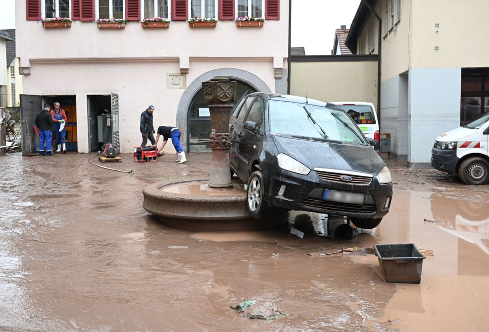 Auf einem Brunnen in Rudersberg steht ein durch ein Hochwasser weggespültes Auto.
