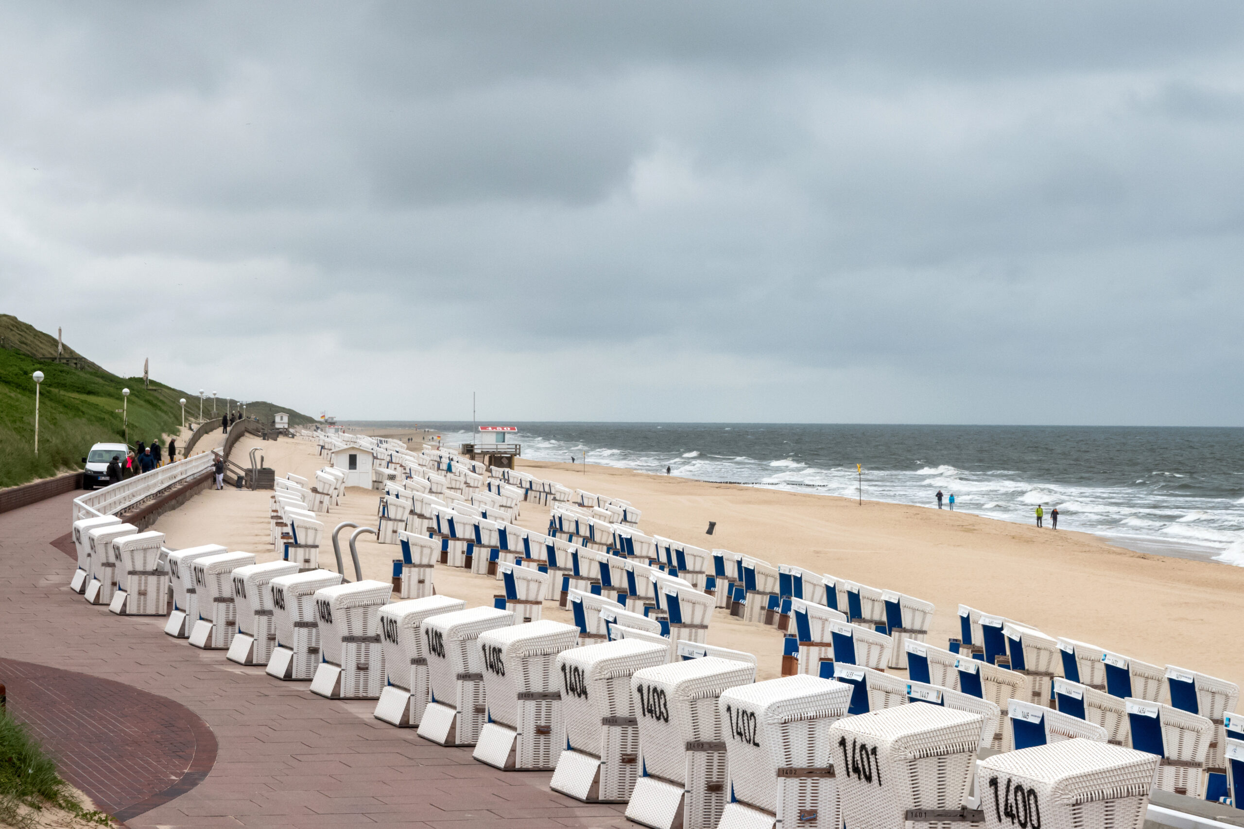 Strandkörbe stehen bei bewölktem Himmel am Strand von Westerland.
