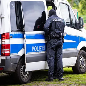 Polizist von hinten an Einsatzwagen
