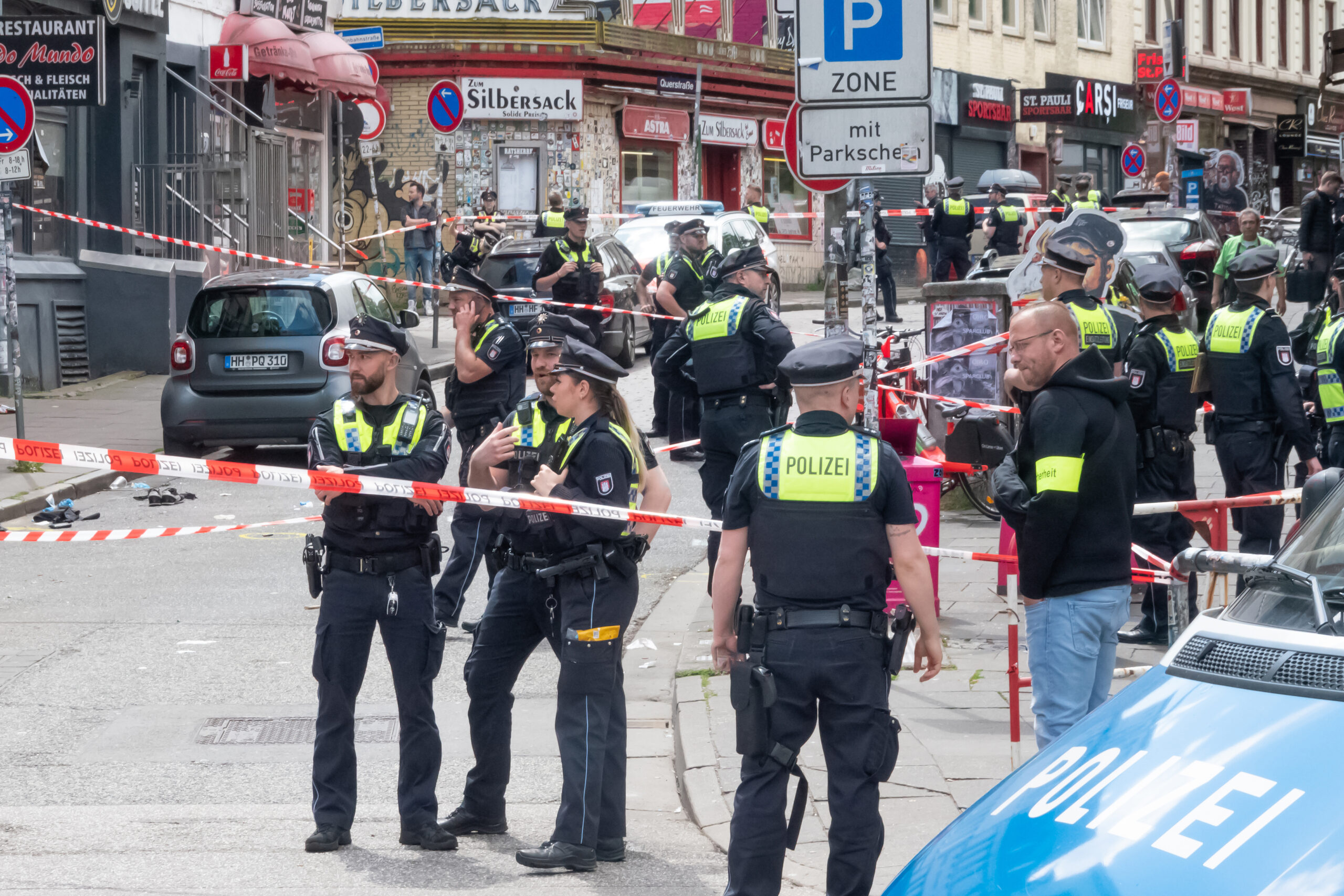 Polizisten stehen am Einsatzort. Die Polizei hat am Sonntag nahe der Reeperbahn in St. Pauli einen mit einem Schieferhammer und einem Molotowcocktail bewaffneten Mann angeschossen.