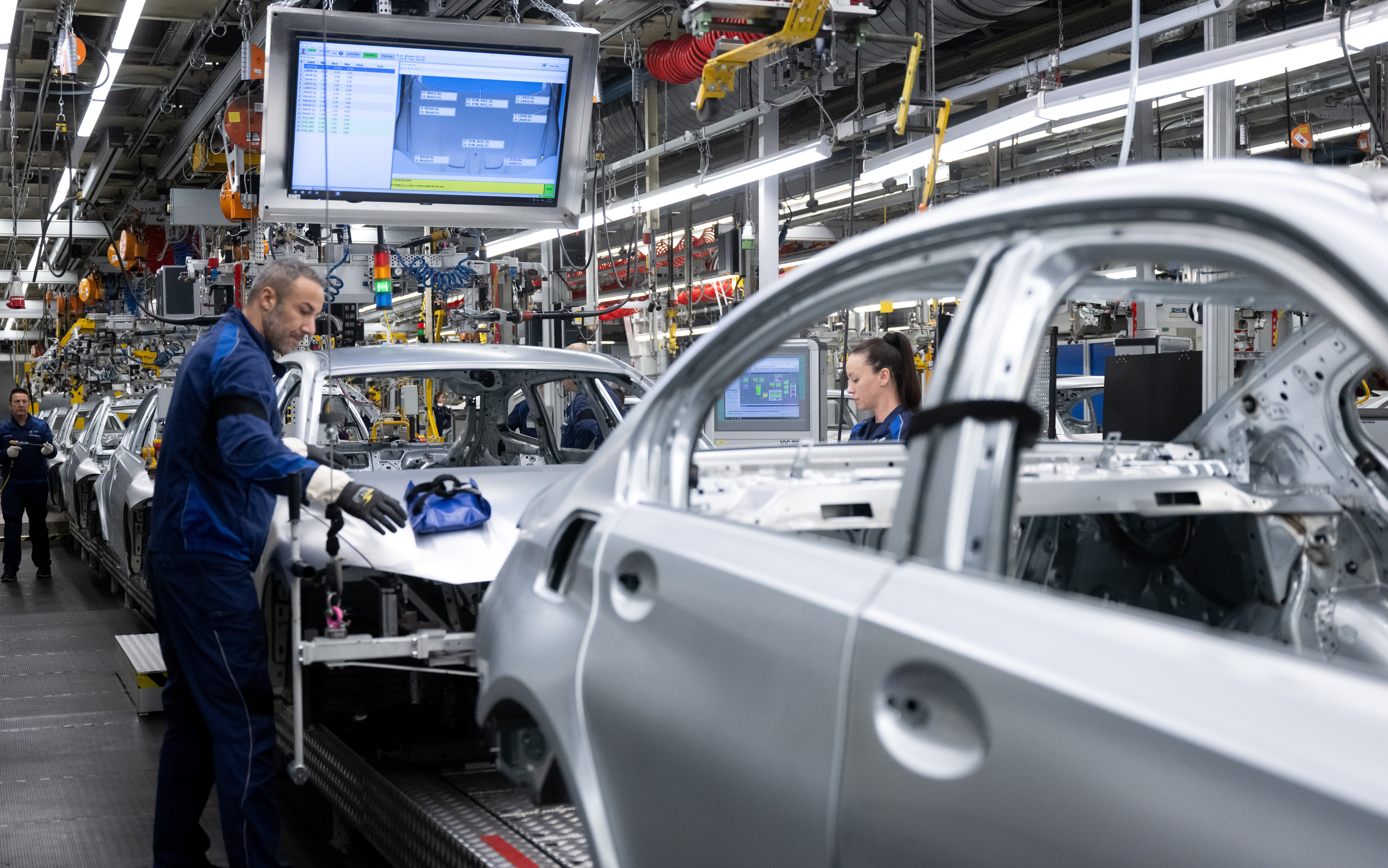 Mitarbeiter von BMW arbeiten im Stammwerk in der Produktion an der Karosserie von Autos.