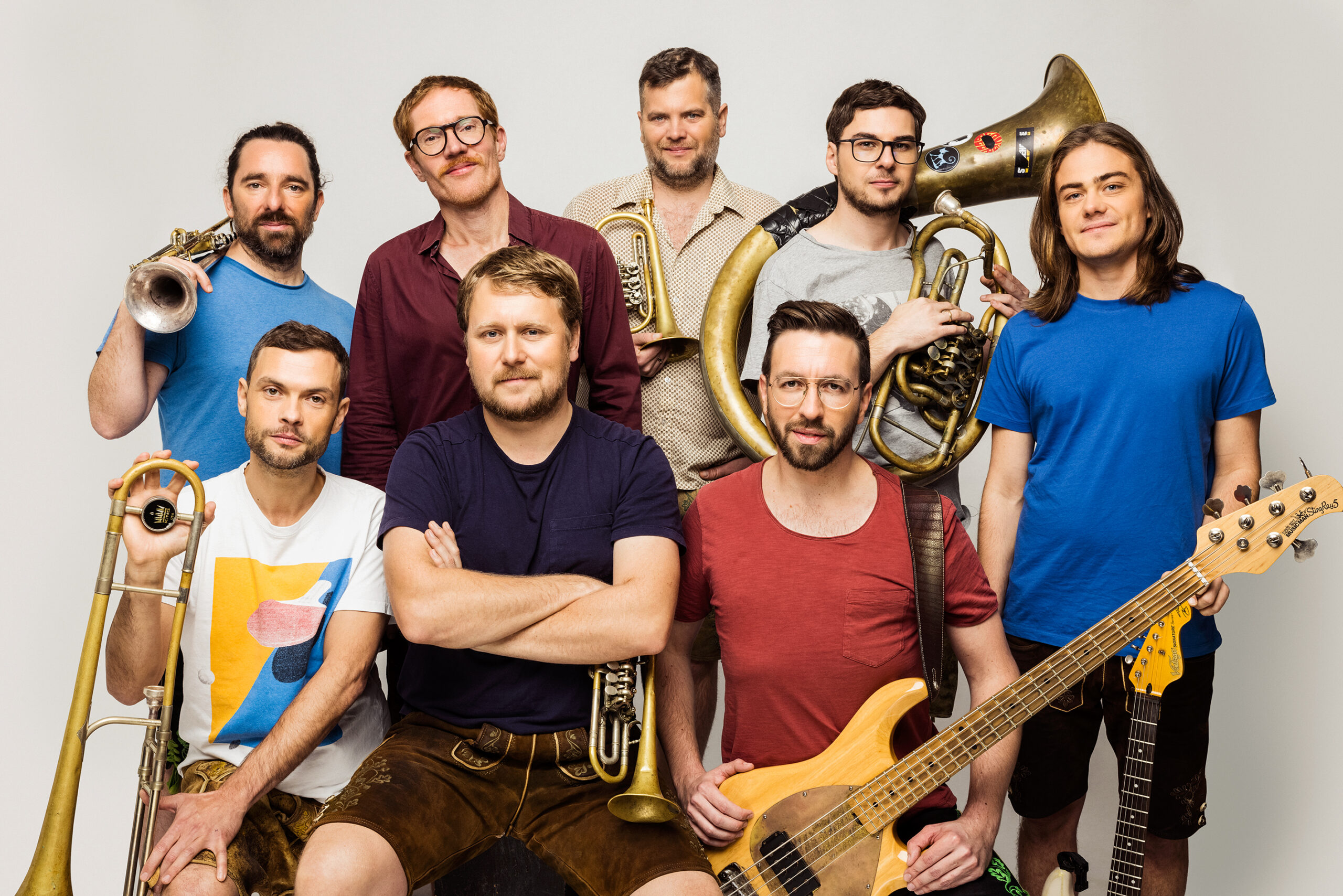 Acht Männer mit Instrumenten, die in die Kamera schauen