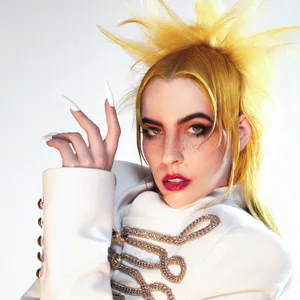 Dorian Electra trägt eine weiße Uniformjacke mit goldenen Verzierungen, die Haare sind blond.