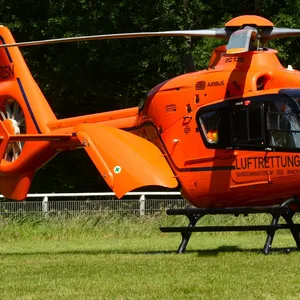 Orangefarbener Rettungshubschrauber auf einer Wiese