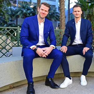 Eric Huwer und Claus Costa sitzen im Anzug nebeneinander