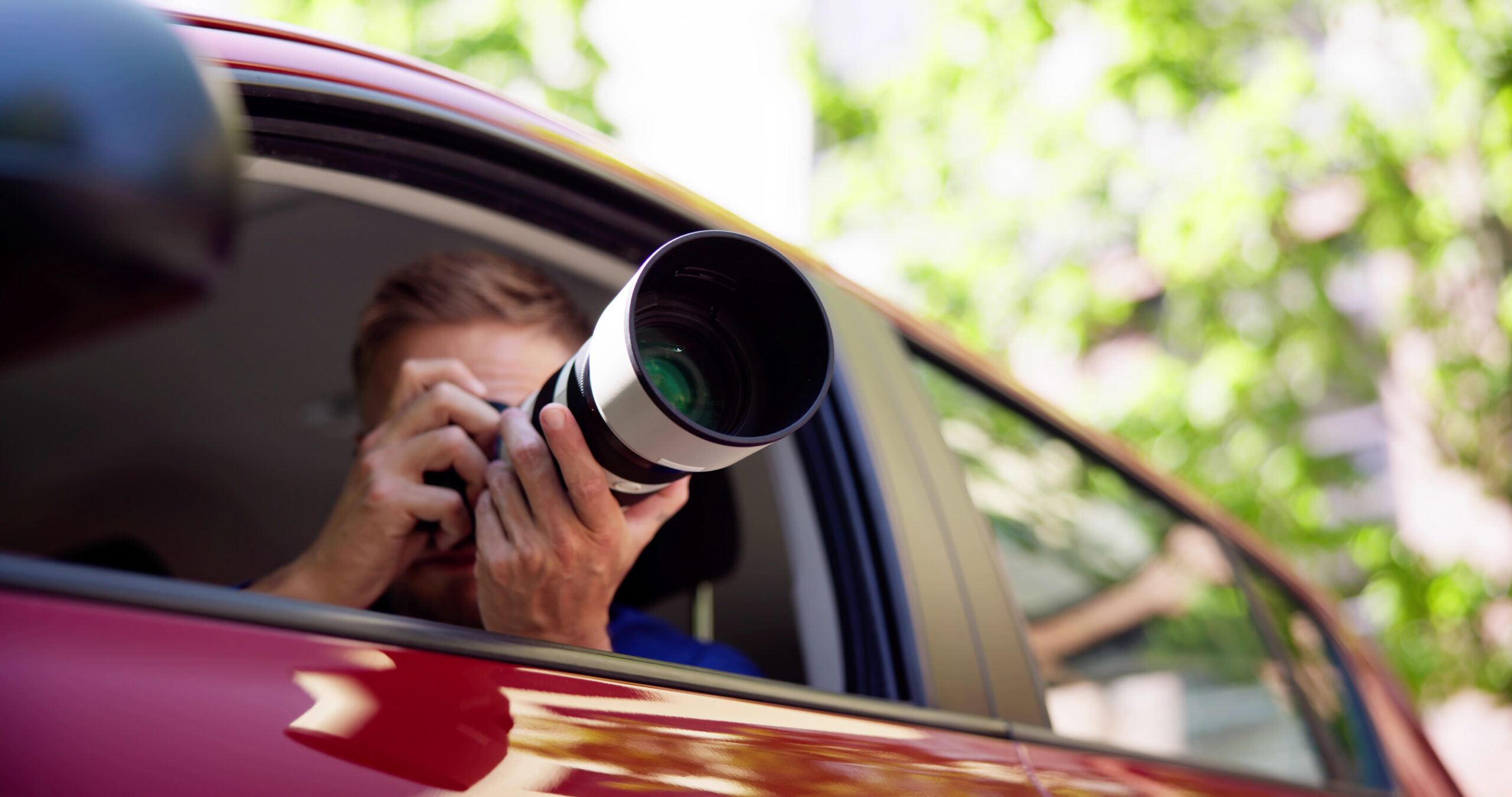 Ein Mann fotografiert mit einer Kamera aus seinem Auto heraus.