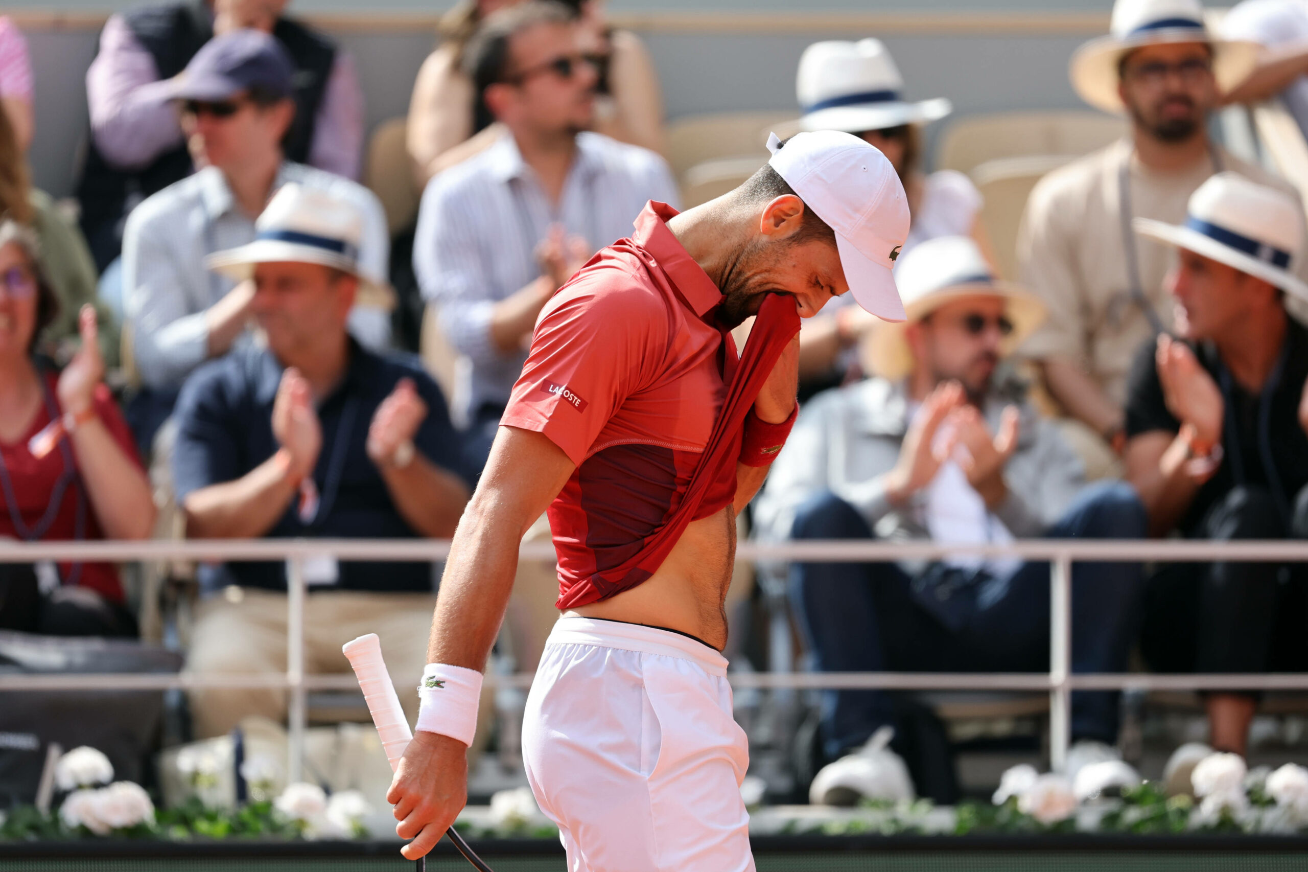 Novak Djokovic wischt sein Gesicht mit dem T-Shirt