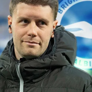 St. Paulis Ex-Trainer Fabian Hürzeler vor dem Wappen seines neuen Vereins
