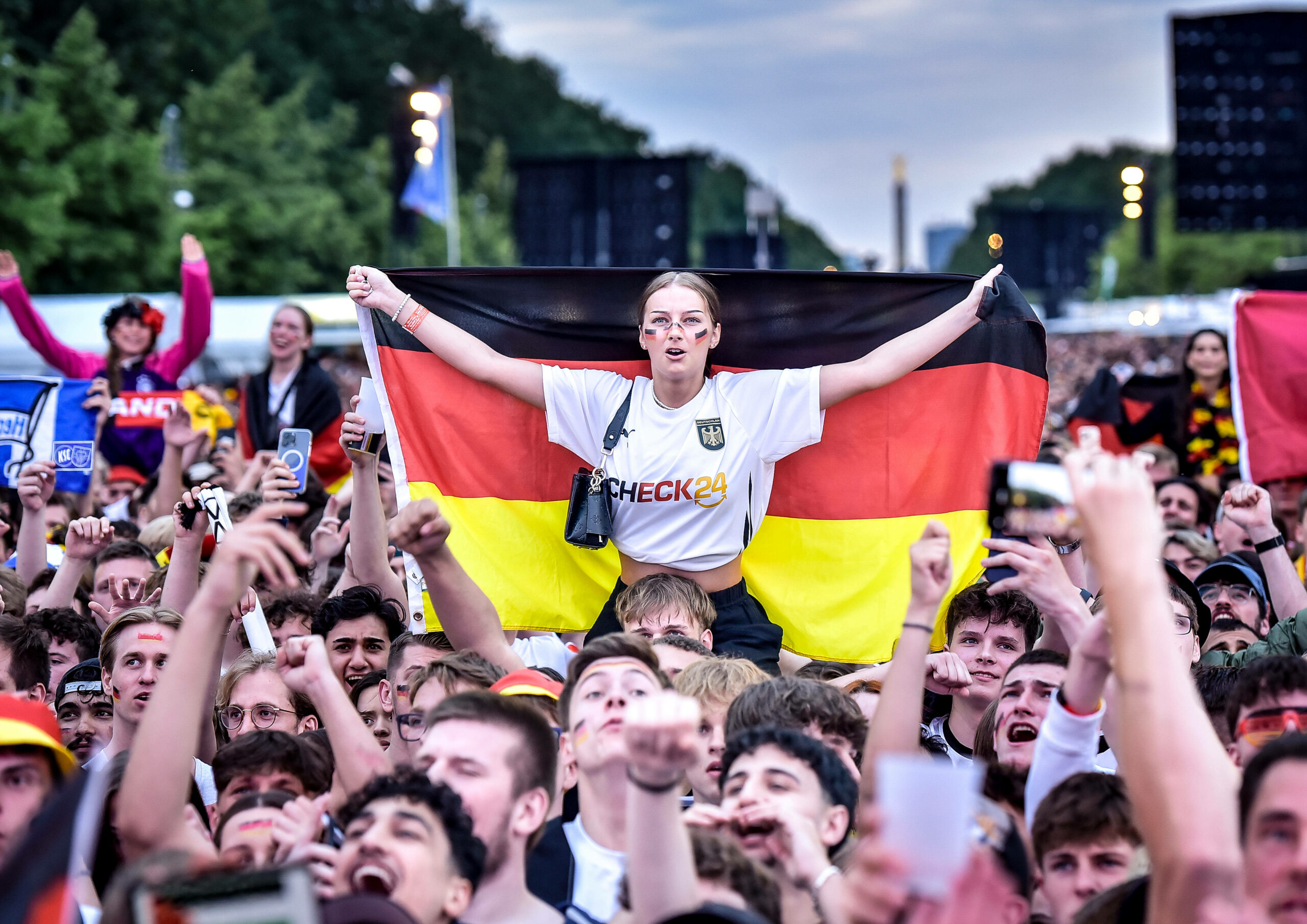 Ein weiblicher Deutschland-Fan hält auf Schultern getragen eine Deutschland-Fahne hoch.