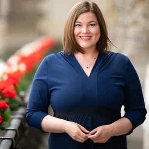 Frau in blauem Kleid vor roten Geranien
