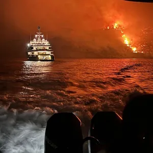 Yacht fährt von Feuer weg