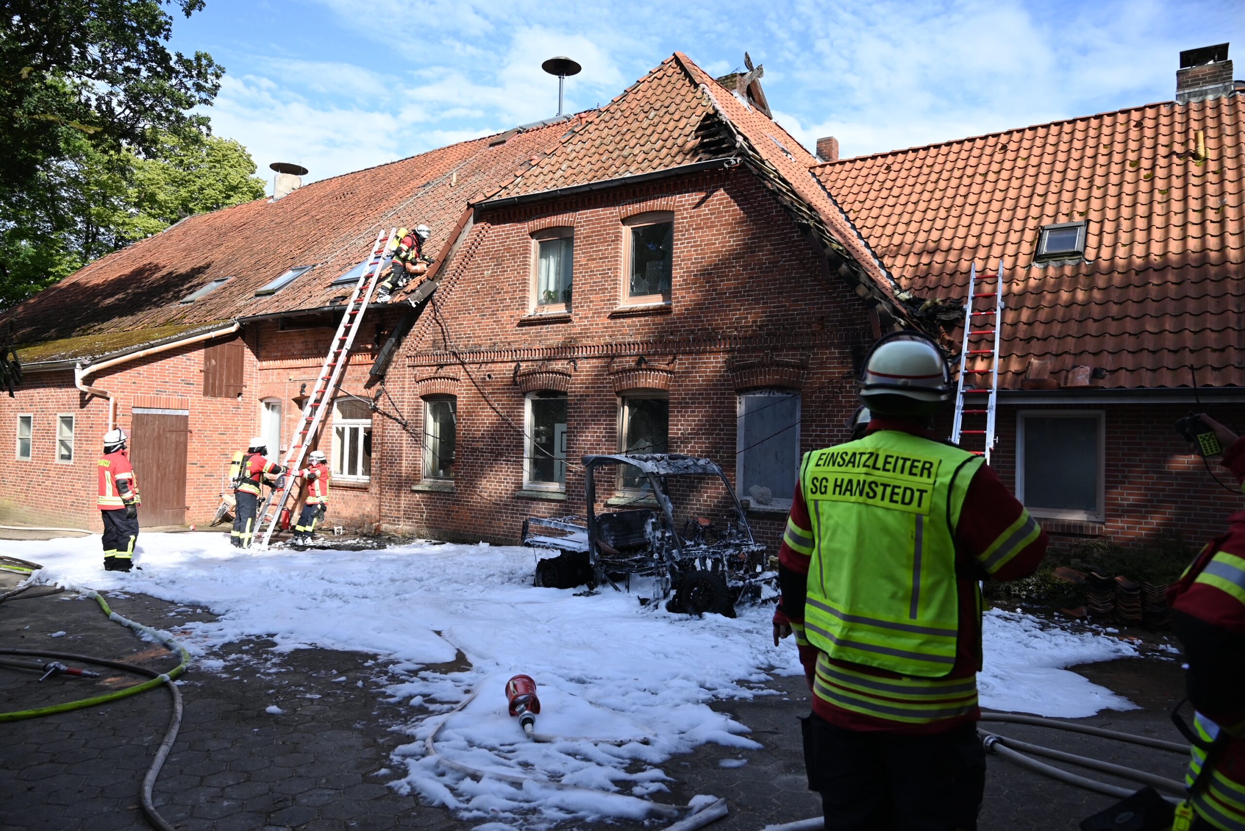 Feuerwehrkräfte stehen um das ausgebrannte Fahrzeug herum.