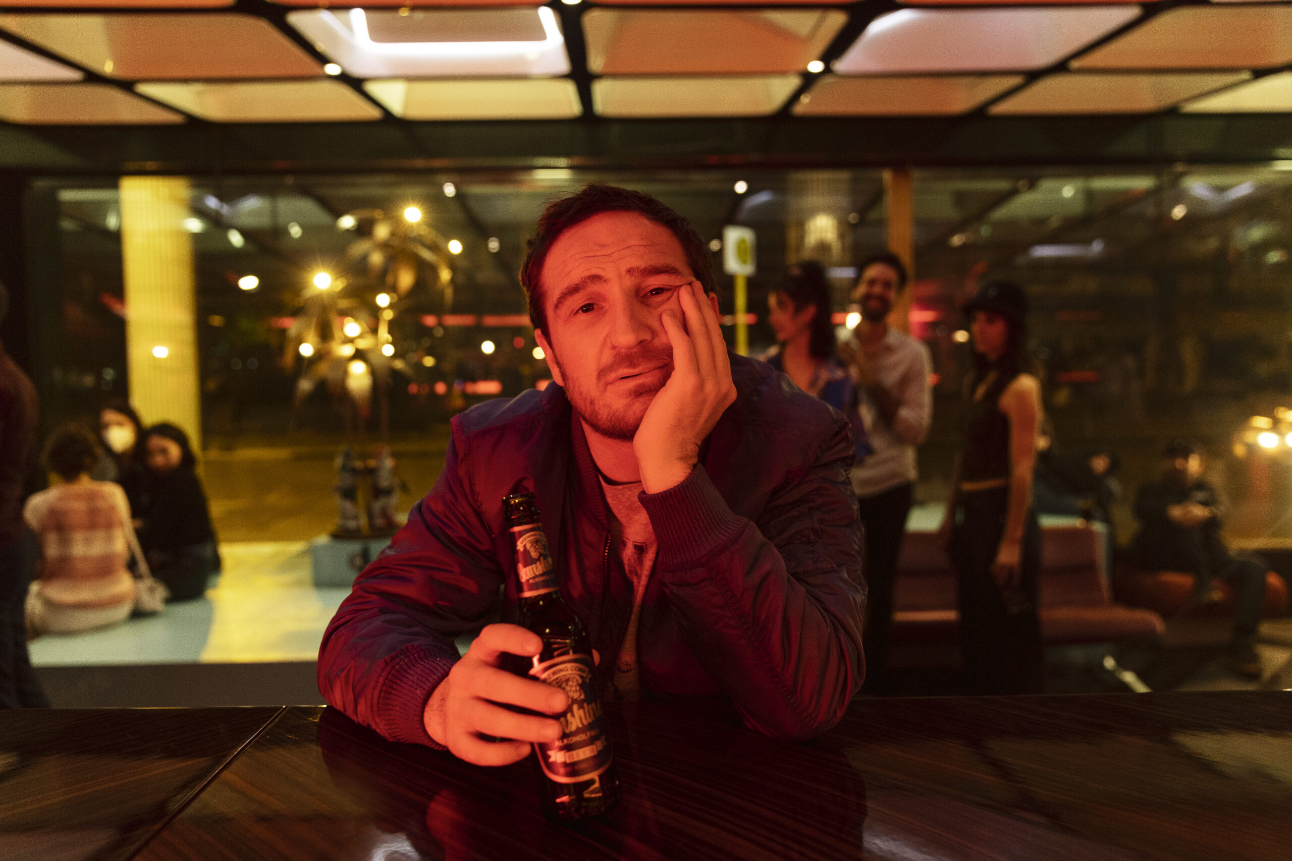 Frederick Lau hält eine Bierflasche in der Hand.