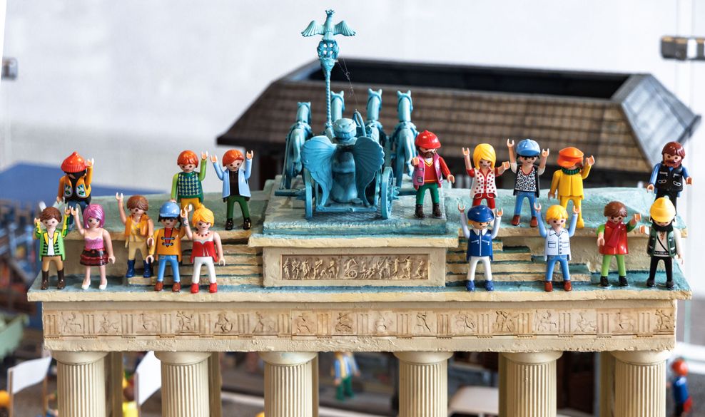 Playmobilfiguren stehen auf einem Modell des Brandenburger Tors.