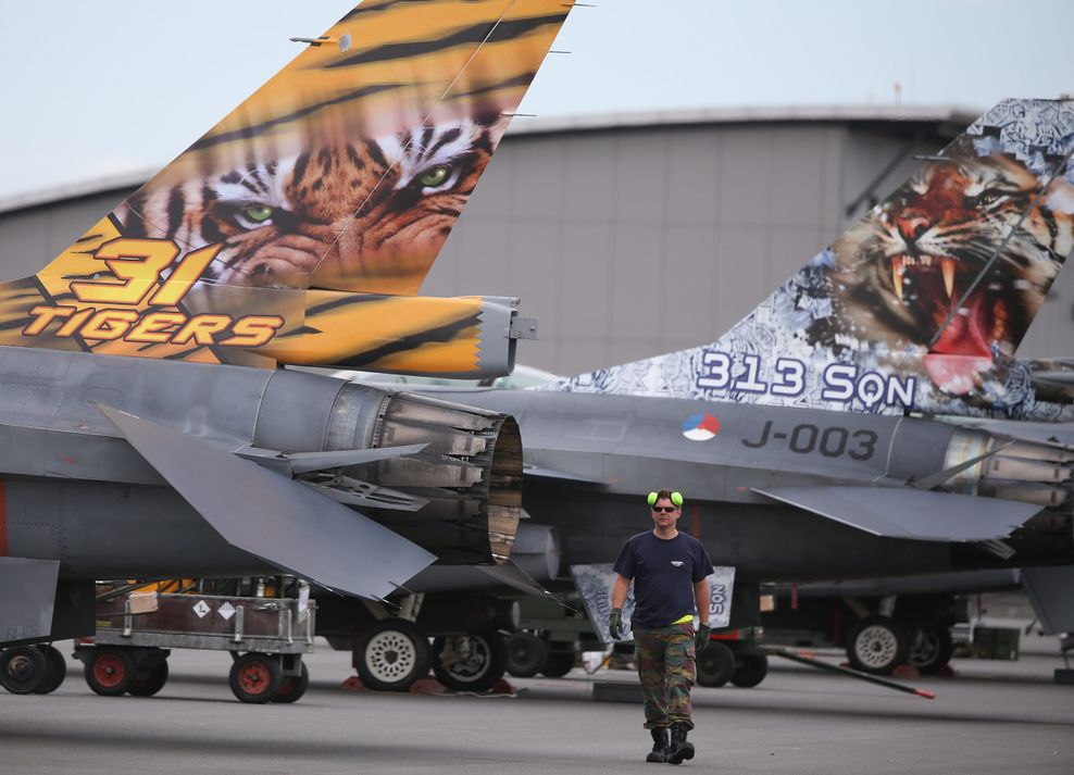 Ein Techniker läuft in Jagel auf dem Fliegerhorst zwischen den bemalten Leitwerken von F-16 Kampfflugzeugen entlang.