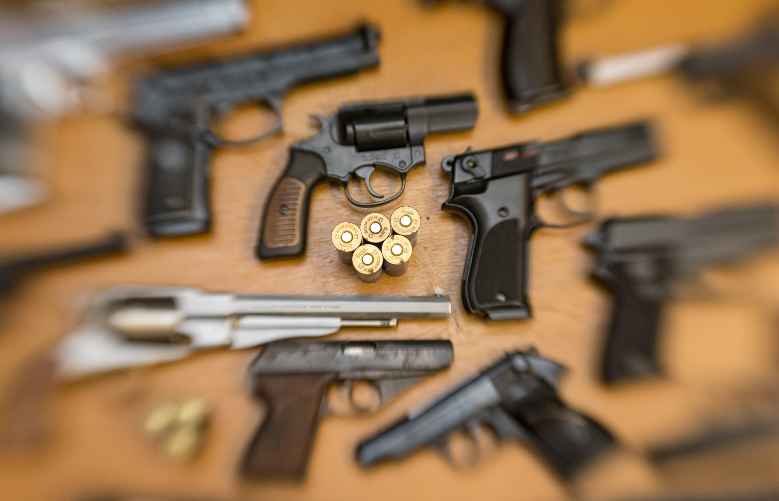 Pistolen, Revolver und Munition liegen auf einem Tisch in einer gesicherten Asservatenkammer.