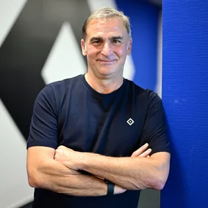 Stefan Kuntz lehnt an eine HSV-Wand
